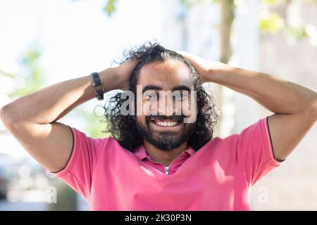 Glücklicher junger Mann mit Händen im Haar Stockfoto