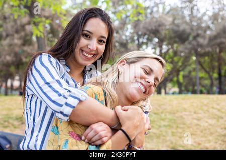 Glückliche junge Frau, die mit einem Freund im Park genießt Stockfoto