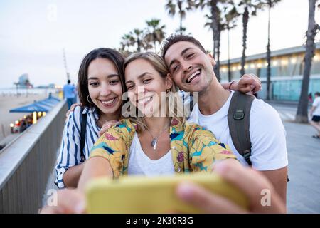 Glückliche junge Frau, die mit Freunden Selfie macht Stockfoto