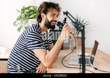 Glücklicher Content-Schöpfer, der Podcast auf dem Mikrofon zu Hause aufzeichnet Stockfoto