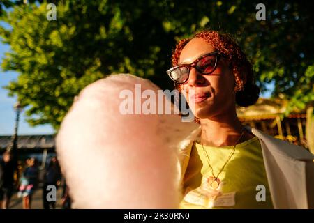 Junge Frau mit Sonnenbrille und Zuckerwatte Stockfoto
