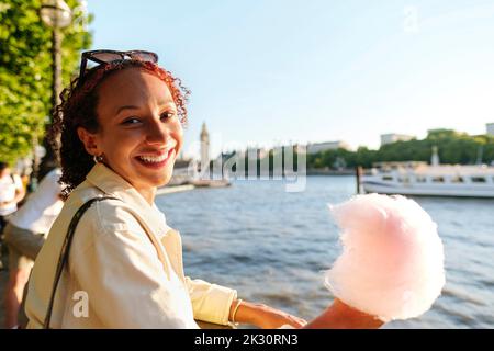 Glückliche Frau mit Baumwollbonbons an der Themse Stockfoto