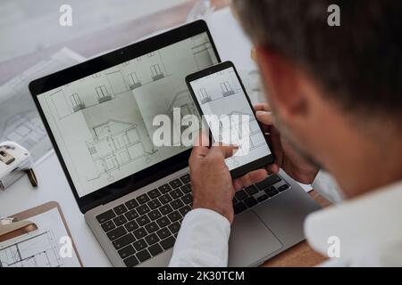 Hände des Architekten, der die Zeichnung auf dem Mobiltelefon im Büro analysiert Stockfoto