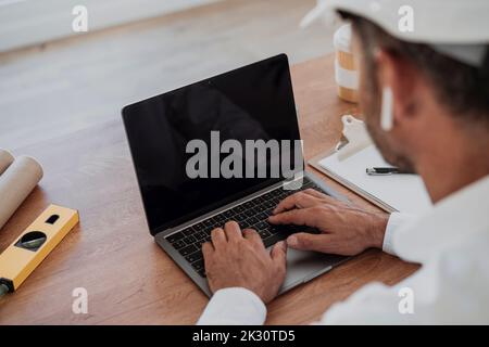 Techniker, die am Schreibtisch einen Laptop benutzen Stockfoto