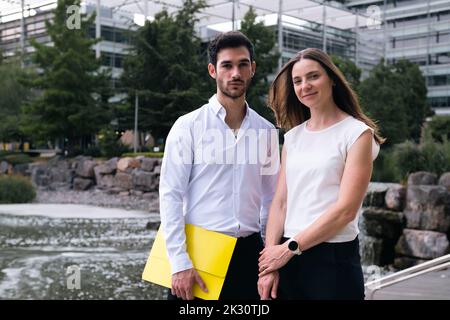 Glückliche Geschäftskollegen stehen vor dem Teich im Büropark Stockfoto