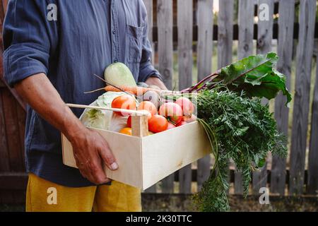 Mann, der eine Kiste voller frischem Gemüse hält Stockfoto