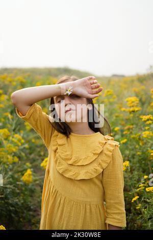 Mädchen mit Blumen, die von einem Verband auf dem Feld aufgeklebt wurden Stockfoto