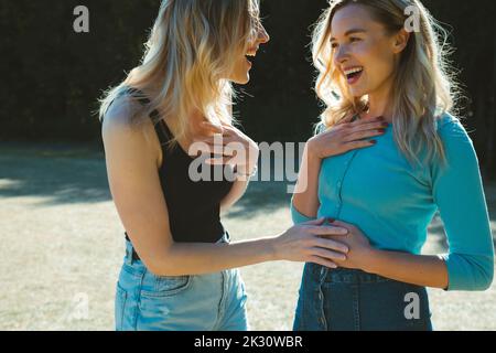 Fröhliche blonde Frau gibt gute Nachrichten über die Schwangerschaft an Freund im Park Stockfoto