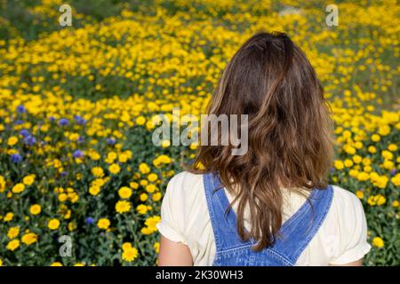 Reife Frau, die vor blühenden Pflanzen im Park steht Stockfoto