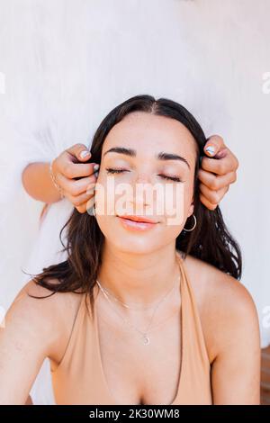 Hands touching face of young woman Stockfoto