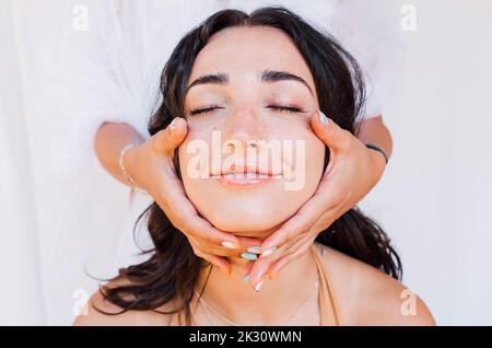 Hände berühren Gesicht der schönen jungen Frau Stockfoto