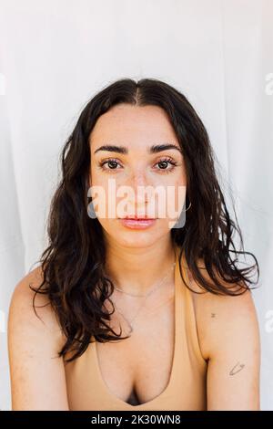 Schöne junge Frau mit langen Haaren vor einer weißen Wand Stockfoto