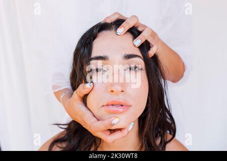 Hands holding head on young woman Stockfoto