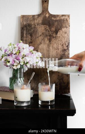 Hand einer Person, die veganen Eiskaffee mit Hafermilch zubereitet Stockfoto