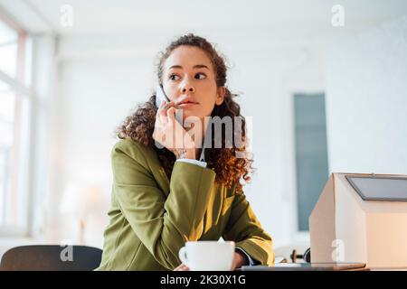 Geschäftsfrau, die auf einem Smartphone am Schreibtisch im Büro sitzt Stockfoto