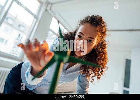 Ingenieur mit lockigen Haaren, der das Windturbinenmodell im Büro analysiert Stockfoto