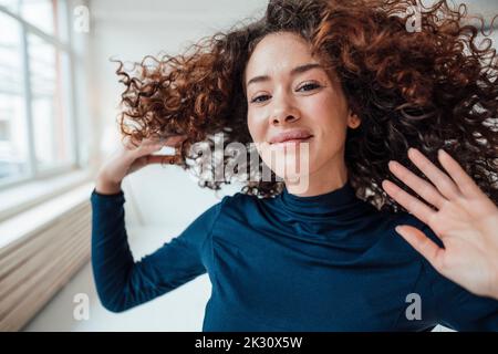 Lächelnde junge Frau, die Haare wirft Stockfoto