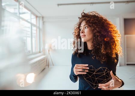 Schöne Frau mit lockigen Haaren hält Herzform Modell Stockfoto