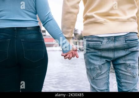 Junges Paar, das die Hände vor dem Fluss zusammenhält Stockfoto