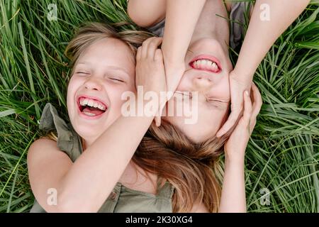 Bruder und Schwester haben Spaß zusammen auf Gras liegen Stockfoto