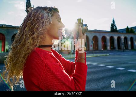 Lächelnde Frau beim Fotografieren durch die Kamera in der Stadt Stockfoto