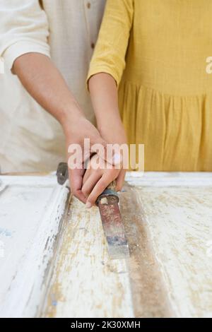 Hände von Vater und Tochter, die Arbeitswerkzeug zusammen an der Tür benutzen Stockfoto