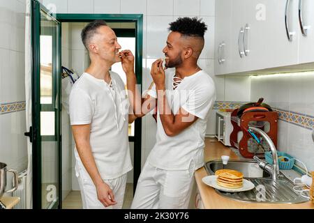 Gay paar essen Pfannkuchen in der Küche zu Hause Stockfoto