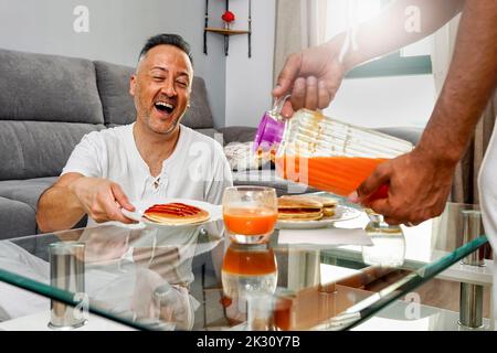 Glücklich reifen Mann Blick auf Freund Gießen Saft in Glas Stockfoto