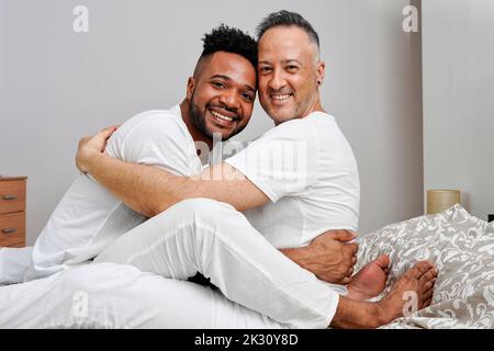 Glücklich Gay Paar umarmt auf Bett zu Hause Stockfoto