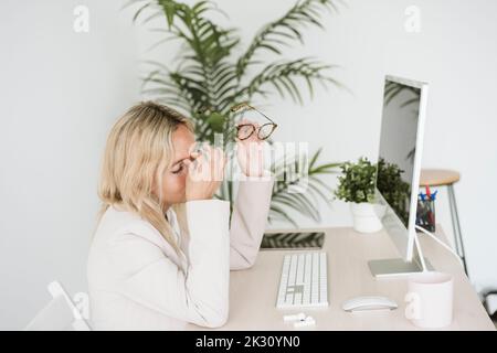 Müde Geschäftsfrau, die im Büro am Schreibtisch sitzt Stockfoto