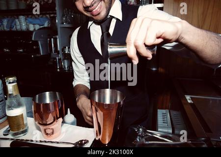 Barkeeper gießt Sirup in den Shaker durch eine Jigger an der Bar Stockfoto