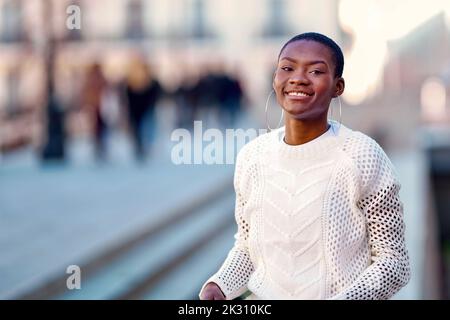 Lächelnde junge Frau mit Kreolen Stockfoto