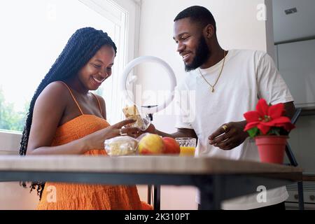 Mann, der zu Hause einer Schwangeren das Frühstück gibt Stockfoto