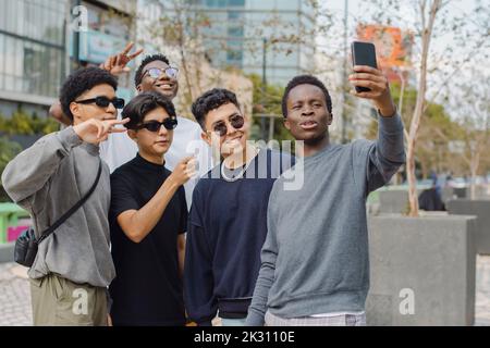 Mann, der Selfie mit Freunden macht, die Friedenszeichen machen Stockfoto