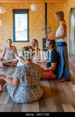 Reife Frau mit Freunden, die im Yoga-Kurs Meditation praktiziert Stockfoto