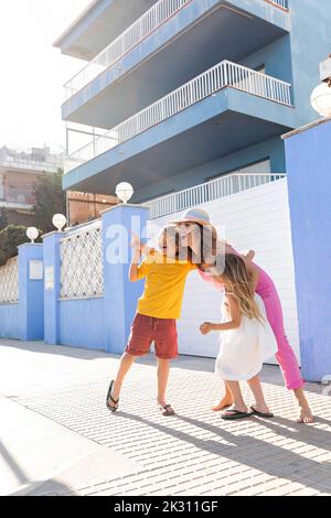 Glückliche Frau, die Spaß mit Sohn und Tochter vor dem Gebäude hat Stockfoto