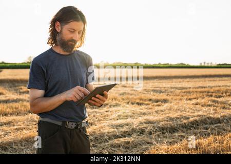 Reifer Landwirt, der an sonnigen Tagen einen Tablet-PC auf dem Bauernhof verwendet Stockfoto