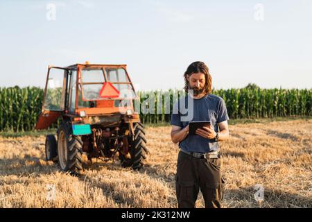 Reifer Landwirt, der Tablet-PC im Feld verwendet Stockfoto