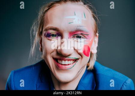 Lächelnder junger Mann mit Make-up im Gesicht Stockfoto