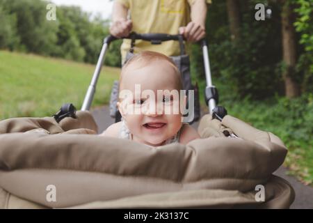 Glückliches Baby Mädchen liegt in Träger mit Vater im Park Stockfoto