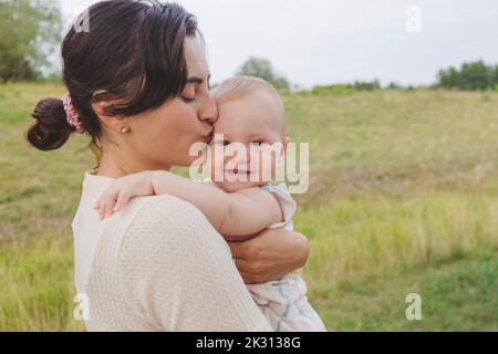 Mutter küsst die Stirn der Tochter im Park Stockfoto