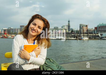 Glückliche Frau mit Tagebuch im Hamburger Hafen Stockfoto