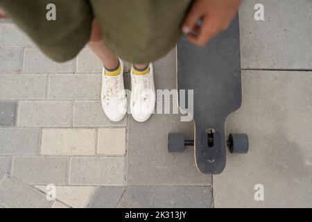 Mädchen, das am Skateboard auf dem Fußweg steht Stockfoto