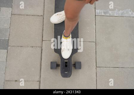 Mädchen, das auf dem Skateboard auf dem Fußweg steht Stockfoto