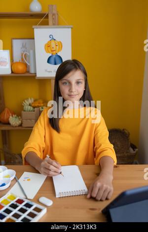 Nettes Mädchen mit Skizze Pad sitzen am Tisch Stockfoto