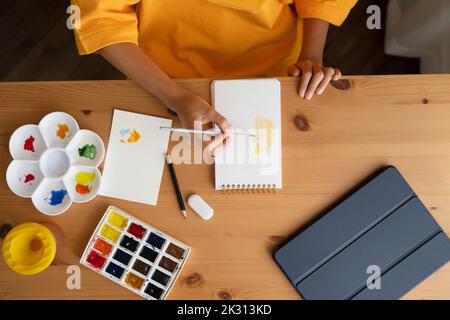 Mädchen mit Aquarellen Malerei auf Skizzenblock am Tisch Stockfoto