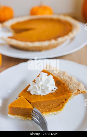 Traditioneller Kürbiskuchen im Herbst mit Schlagsahne auf dem Teller aus nächster Nähe. Thanksgiving- Stockfoto