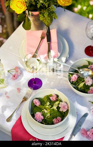 Eleganter, im Frühling dekorierter Tisch mit essbaren Blumen Stockfoto