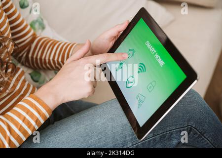 Nahaufnahme einer Frau, die ein digitales Tablet mit Smart-Home-App nutzt Stockfoto