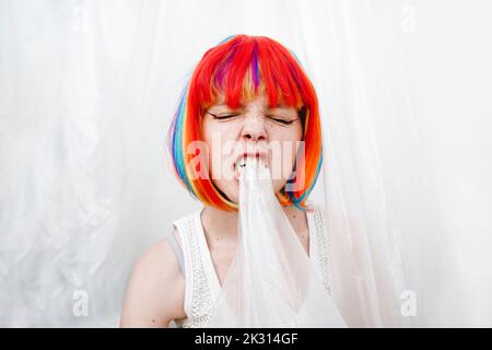 Wütende Frau mit bunt gefärbten Haaren beißenden Kunststoff Stockfoto